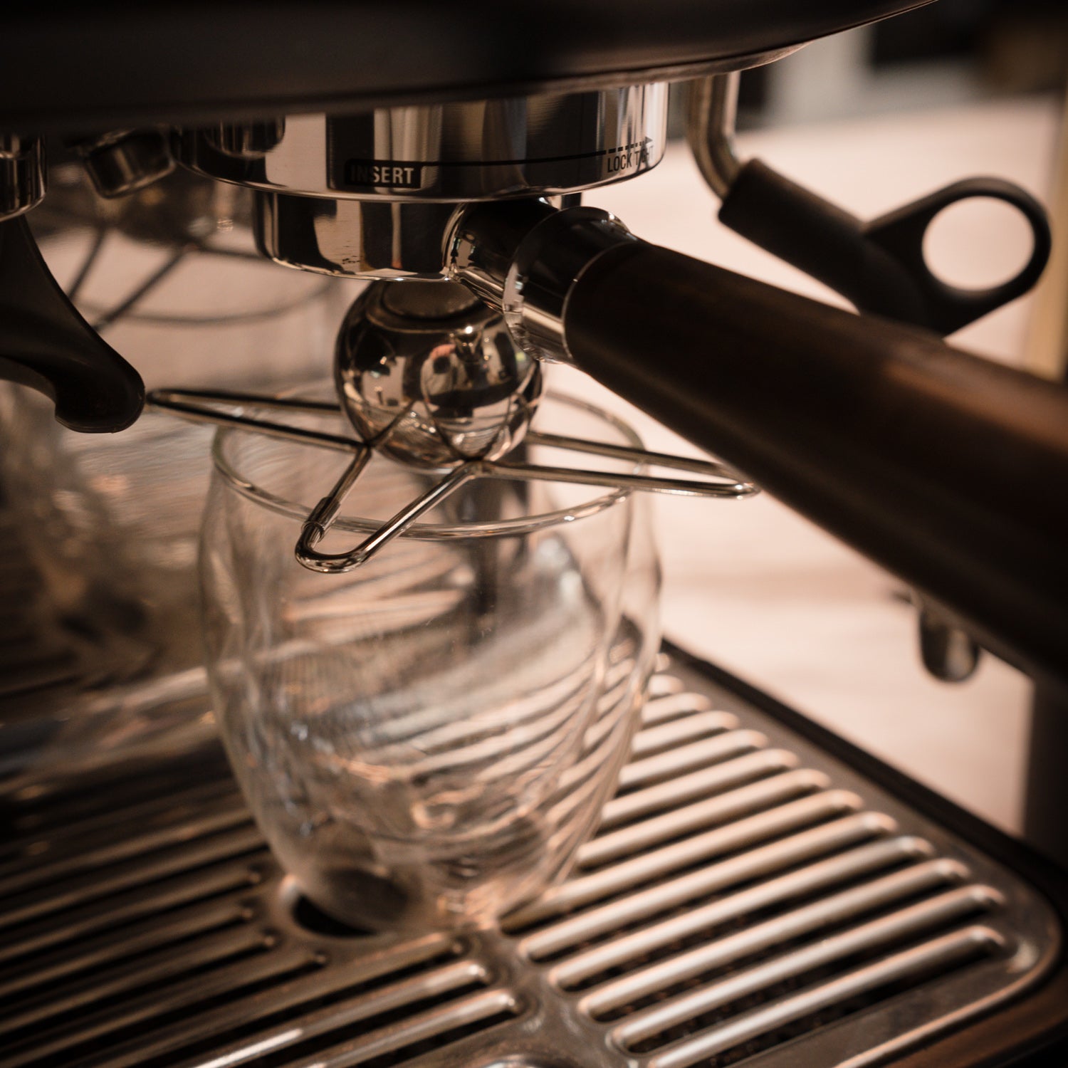 Close-up of an espresso machine with a clear glass container underneath with a chilling ball atop.