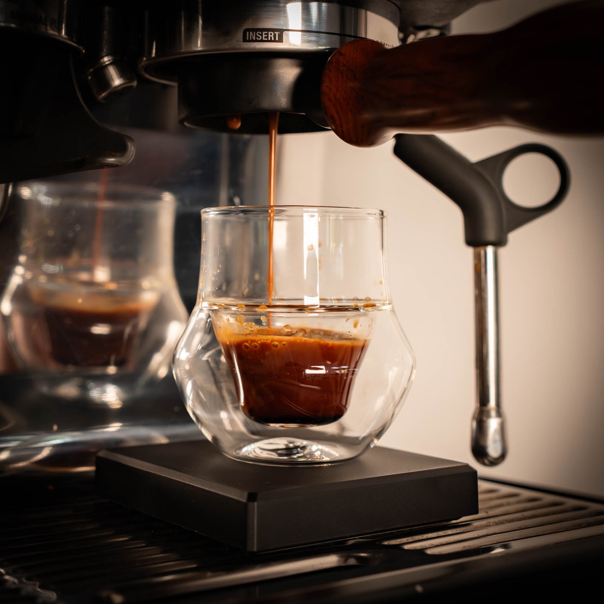 Espresso being poured into a glass from a coffee machine.